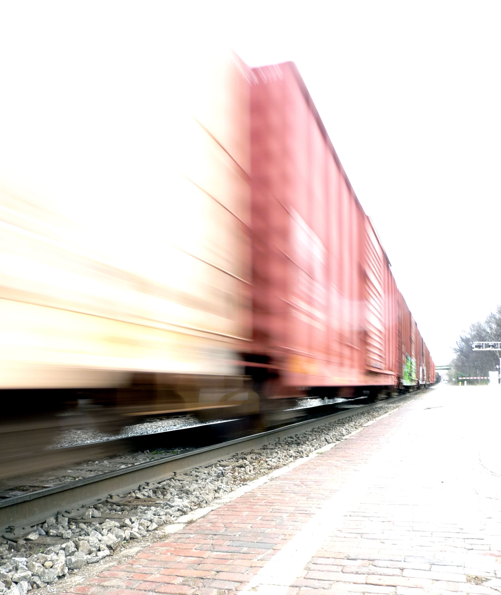 Motion-blurred freight cars rushing past to the left side of a brick train platform