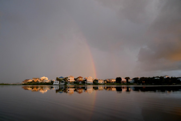 Looking across a lagoon at beach houses with a rainbow over the Gulf of Mexico in the background